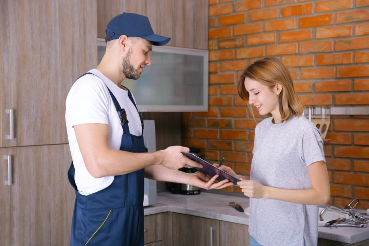 Woman signing receipt for plumber service at home